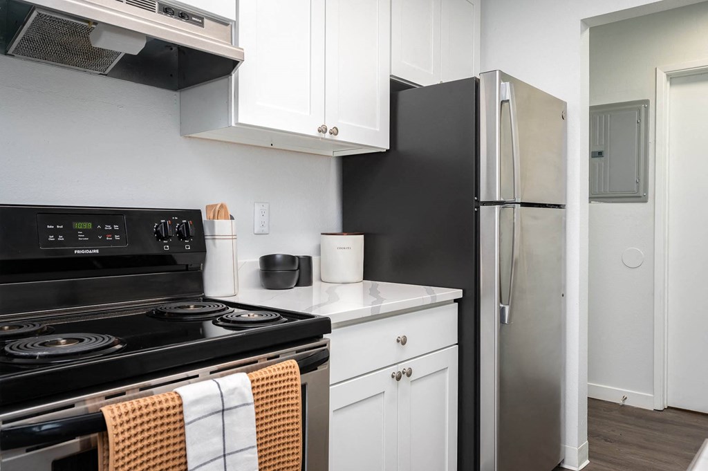 a kitchen with black appliances and white cabinets and a refrigerator